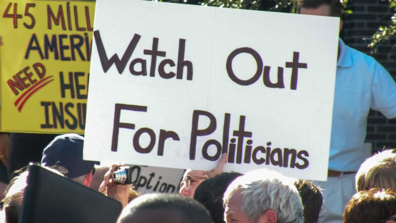 A protester at a political rally holds up a sign that says "Watch Out For Politicians." | Hevanmiller | Dreamstime.com