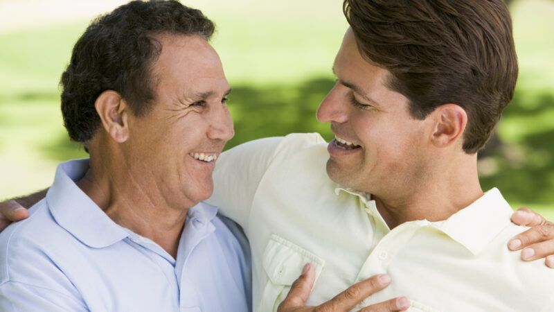 Two men hug in a public park. | Monkey Business Images | Dreamstime.com