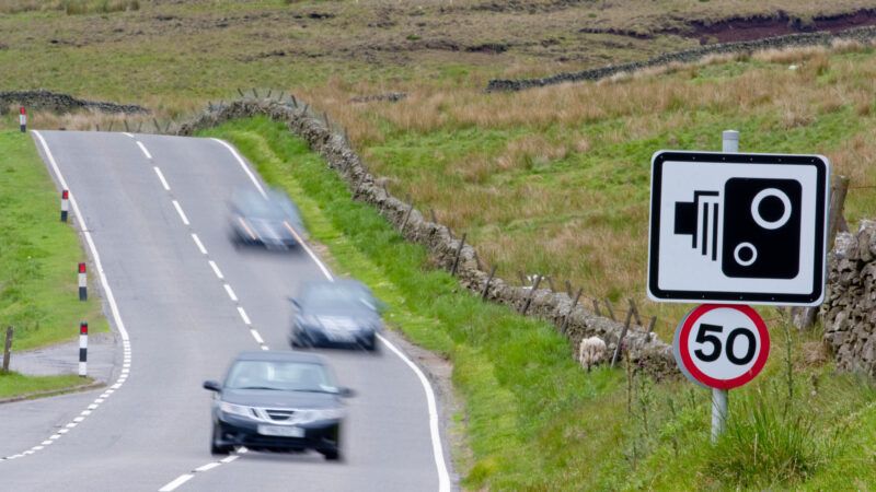 Cars speed down a highway in the U.K., with a sign indicating a speed camera is in use. | Ian Keirle | Dreamstime.com