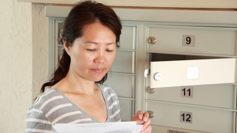 A woman checks the mail from her mailbox in an apartment building. | Cupertino10 | Dreamstime.com