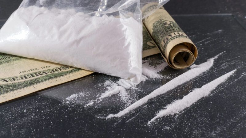 Big Bag and lines of cocaine on a glass surface with a rolled up one hundred dollar bill | DPST/Newscom