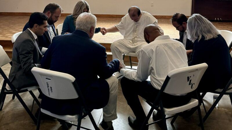Robert Roberson praying with lawmakers | Squire Patton Boggs