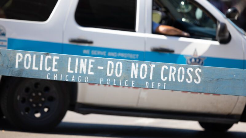 Chicago Police Department vehicle, with a wooden barrier that says "Police Line - Do Not Cross" in the foreground. | Roberto Galan | Dreamstime.com