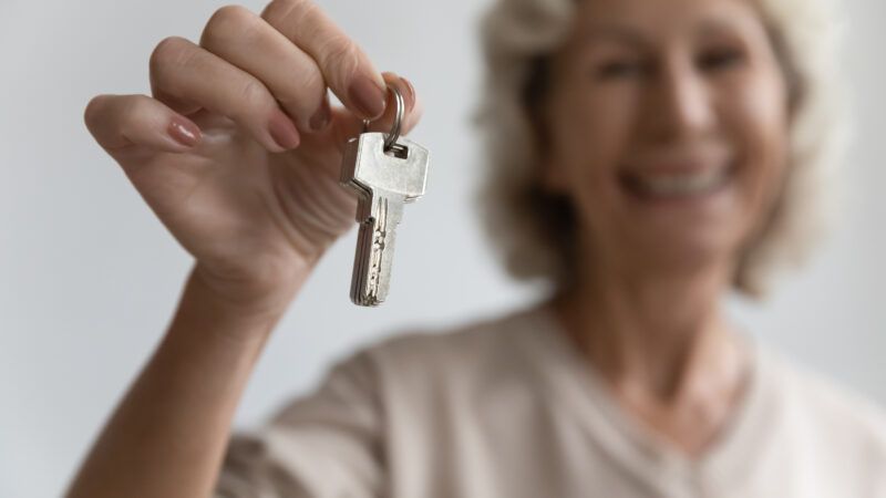 An older woman holds up a set of keys. | Fizkes | Dreamstime.com