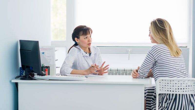 A doctor in her office speaks with a woman during a consultation. | Roman Kosolapov | Dreamstime.com