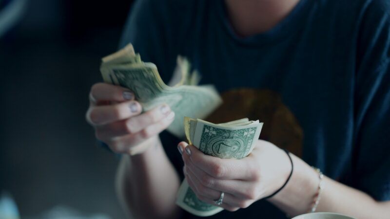 Someone counting a stack of dollar bills | Photo by <a href="https://unsplash.com/@sharonmccutcheon?utm_source=unsplash&utm_medium=referral&utm_content=creditCopyText">Alexander Grey</a> on <a href="https://unsplash.com/photos/focus-photography-of-person-counting-dollar-banknotes--8a5eJ1-mmQ?utm_source=unsplash&utm_medium=referral&utm_content=creditCopyText">Unsplash</a>       