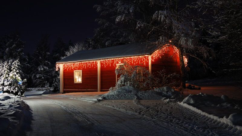 A red, snow-covered cottage pictured at night | Roman Rodionov/Dreamstime.com