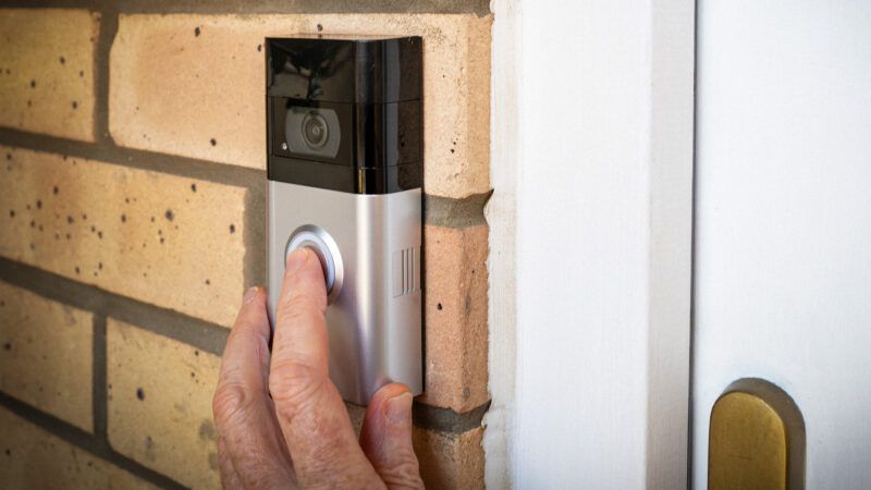 A hand presses a Ring video doorbell, attached to a brick wall. | Nsbeer/Dreamstime