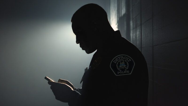 A Detroit Police officer, in shadow, scrolls through a cell phone. | Illustration: Midjourney/Wikimedia Commons