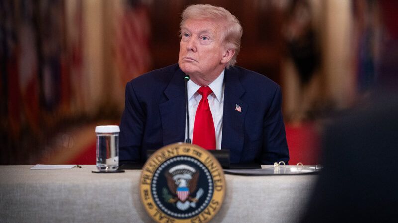 President Donald Trump sits at a table behind the presidential seal. | Sipa USA/Newscom