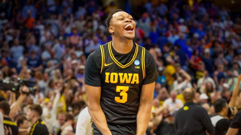 Iowa Hawkeyes forward Cam Manyawu celebrates on a basketball court, with a crowd of fans behind him. | Photo: Jefferee Woo/ZUMA Press/Newscom