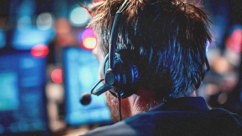 A 911 dispatcher with a headset sits in front of a screen. | Illustration: Midjourney