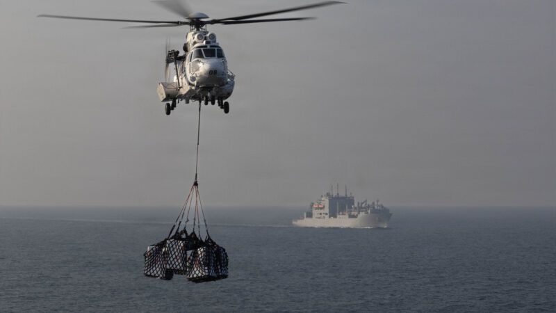 A Eurocopter AS565 Panther helicopter transports cargo to the flight deck of Nimitz-class aircraft carrier USS Abraham Lincoln (CVN 72) during a replenishment-at-sea with Lewis and Clark-class dry cargo ship USNS Carl Brashear (T-AKE-7) in support of Operation Epic Fury, March 18, 2026. | U.S. Navy
