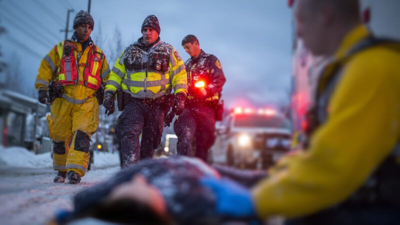 Paramedics approach someone on the ground in cold weather. | Midjourney