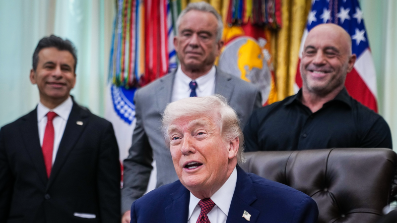 Trump sits in the Oval Office as he announces his executive order on psychedelics, flanked by people like Joe Rogan and RFK Jr. | Sipa USA/Newscom