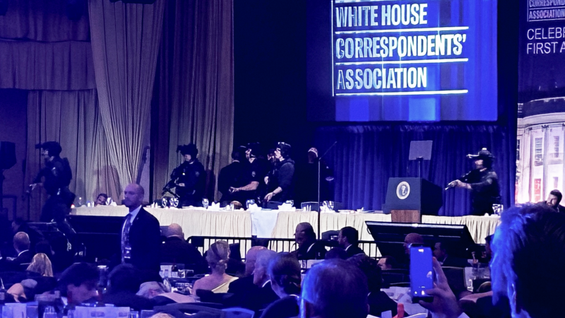 Police officers escort people off stage at the 2026 White House Correspondents' Association dinner. | Jason Dick/CQ Roll Call/Newscom