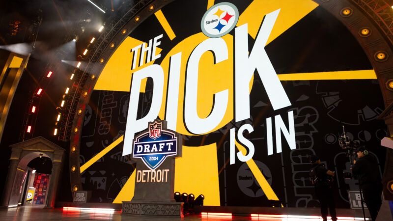 A giant screen with a yellow and black background and the Pittsburgh Steelers logo says "THE PICK IS IN," behind a lectern with a logo that says "NFL DRAFT 2024 DETROIT." | Photo: John Smolek/Icon Sportswire EDG/John Smolek/Icon Sportswire/Newscom