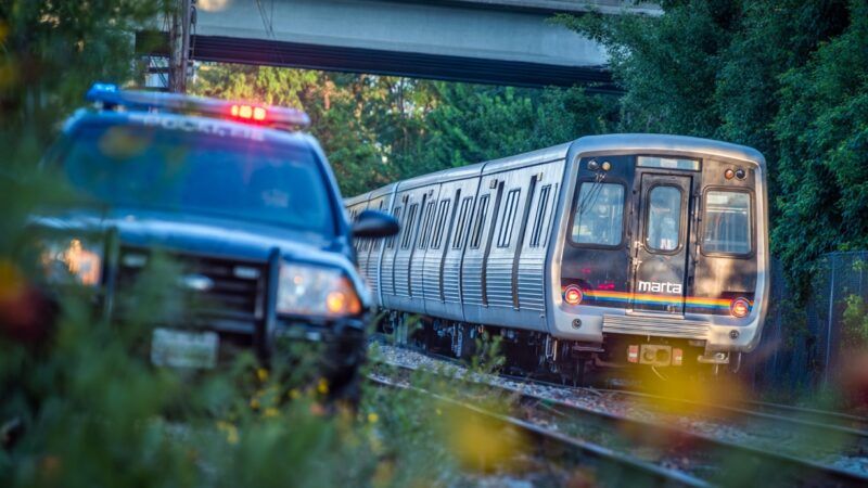 A police car in Atlanta drives alongside a MARTA train. | MidJourney