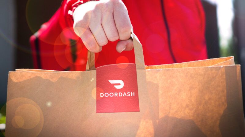 DoorDash delivery person holding a bag. | Envato