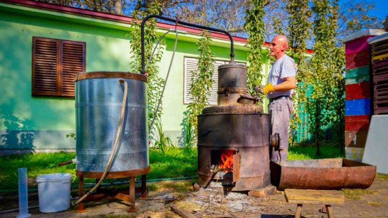 A man operates a hand-crank moonshine still in the woods. | DPST/Newscom