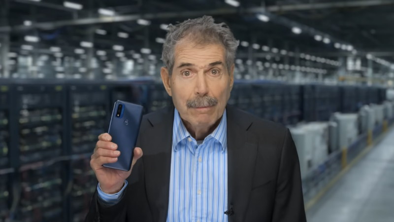 John Stossel holds a phone with a data center as a backdrop | Stossel TV