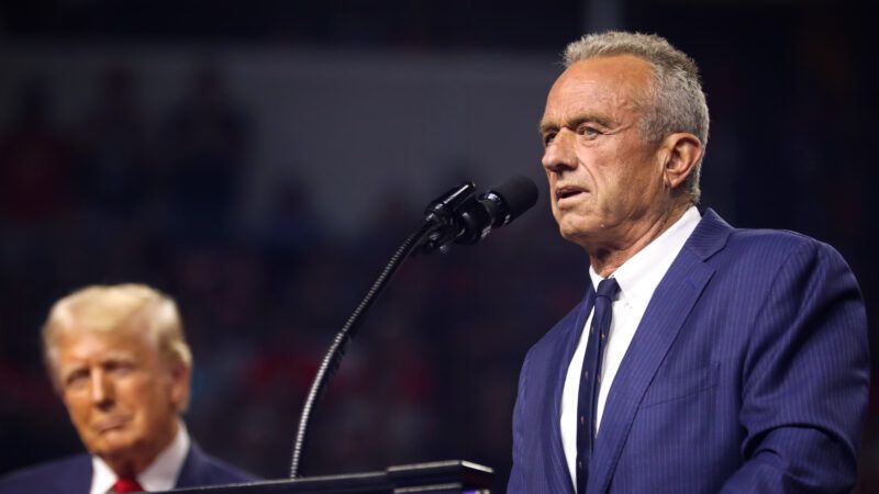 RFK Jr. speaks at a microphone while Trump looks on in the background | Gage Skidmore/ZUMAPRESS/Newscom