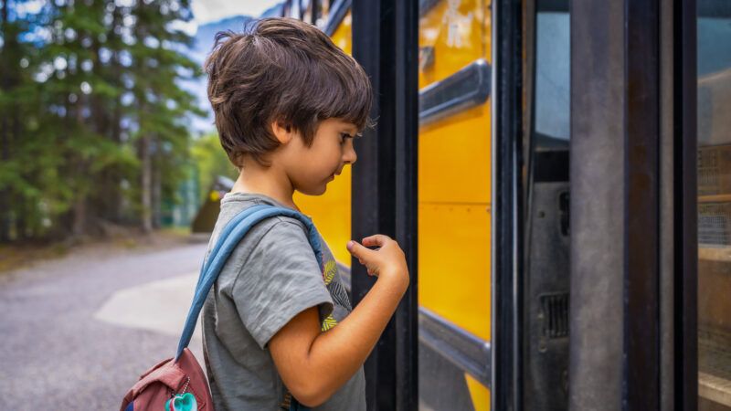 A young boy tentatively gets on a yellow school bus. | imageBROKER/Unai Huizi/Newscom