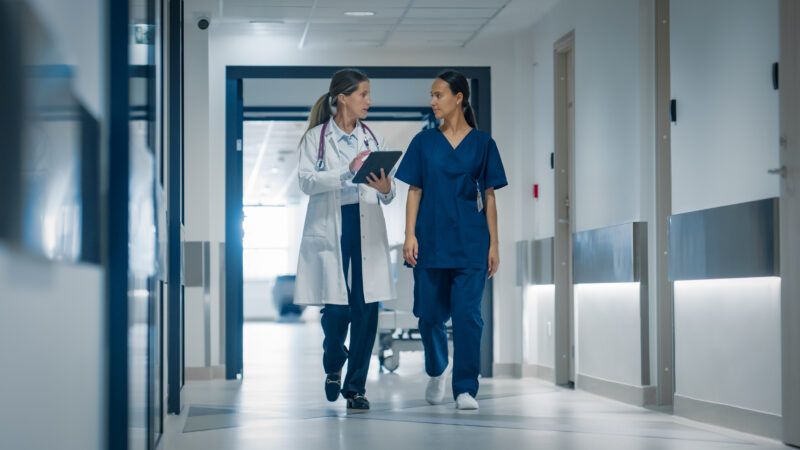 A doctor and a nurse walk down the hall of a hospital. | GORODENKOFF PRODUCTIONS/SCIENCE PHOTO LIBRARY/Newscom