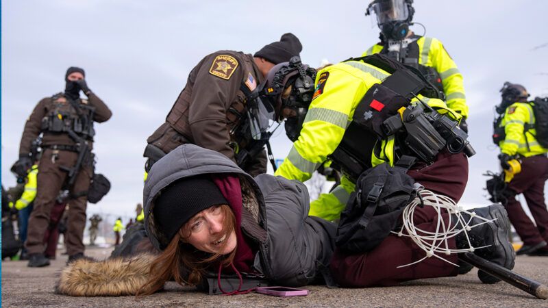 A woman being held on the ground by law enforcement officers | Photo: Whipple Building immigration protest in Minneapolis, Minnesota, in February 2026; Alex Kormann/The Minnesota Star Tribune/Getty