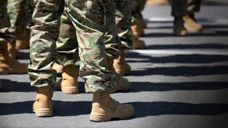 Several uniformed service members wearing camouflage pants and tan combat boots stand in formation. | Photo: Ilia Torlin/Dreamstime.
