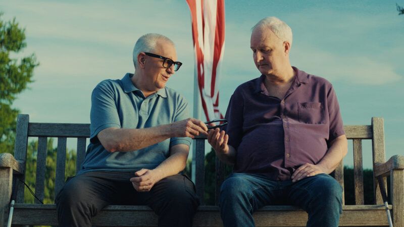 Two men sitting on a bench with one of them wearing Meta glasses | Photo: Meta