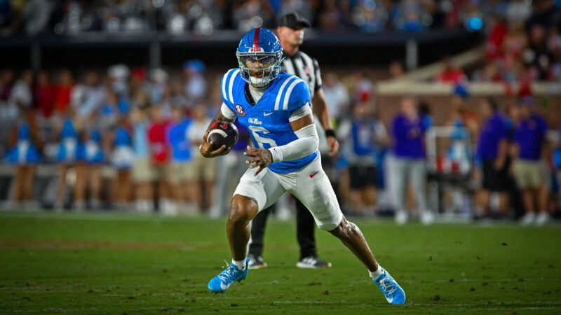 Trinidad Chambliss, in a blue Ole Miss football jersey and helmet, runs with the football held in his right arm. | Photo: Austin Mcafee/Cal Sport Media/Newscom