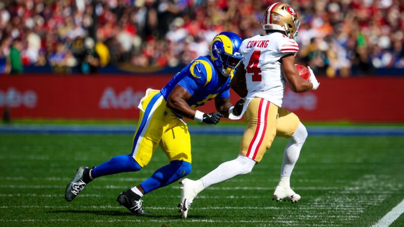 A San Francisco 49ers runs away from the camera with a football, while a Los Angeles Rams player tries to tackle him. | Photo: Chris Putnam/ZUMAPRESS/Newscom