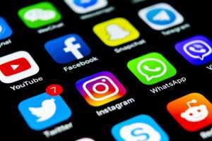 A smartphone screen depicting social media apps YouTube, Facebook, Snapchat, Telegram, Twitter (now X), Instagram, Whatsapp, Skype, Reddit, etc.