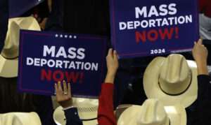 People hold up "mass deportation now" signs at the 2024 Republican National Convention.