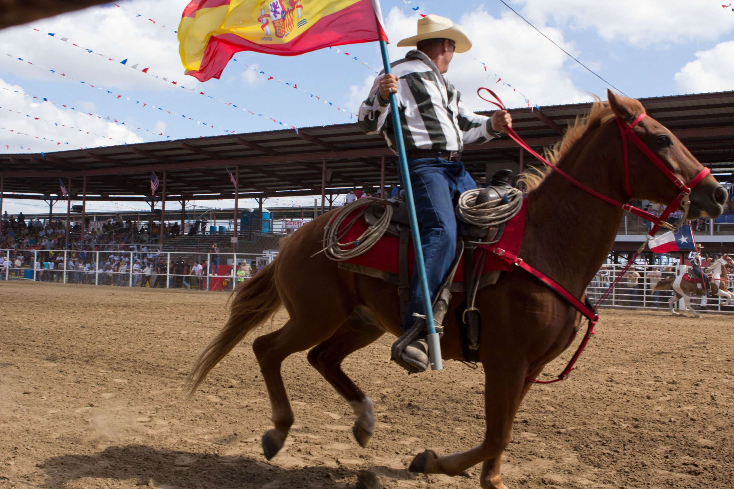 A photo of a man riding on a horse while holding a Spanish flag