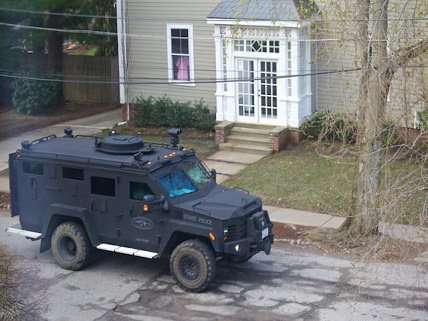 Woman looks on as armored police vehicles rolls down street