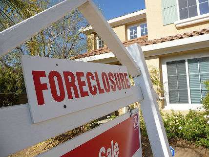 A foreclosure sign hangs in front of a house.