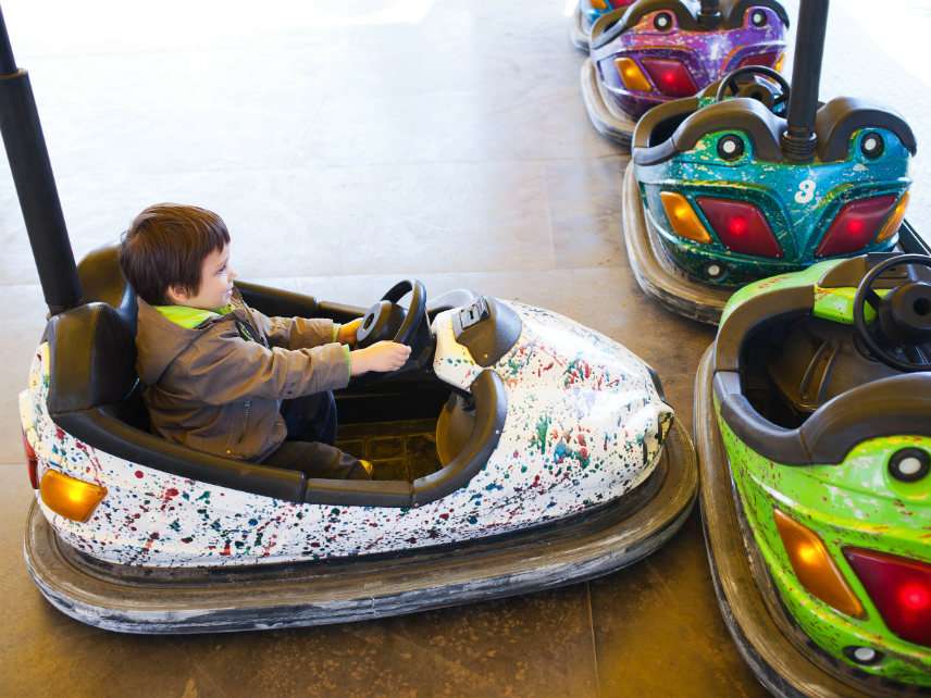 Kid in electric bumper car, amusement park