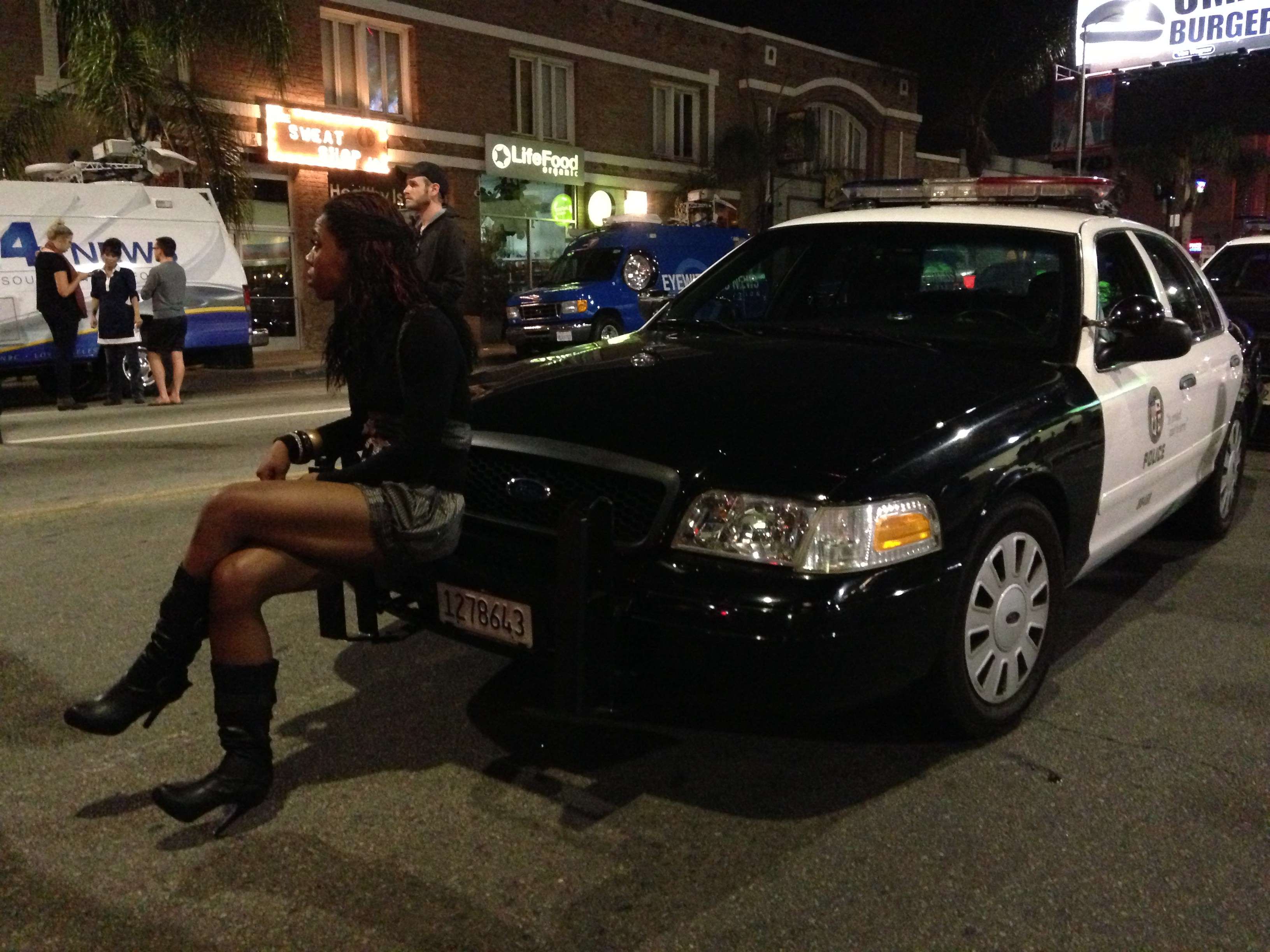 Woman sits on front of LAPD squad car watching protestors July 15, 2013.