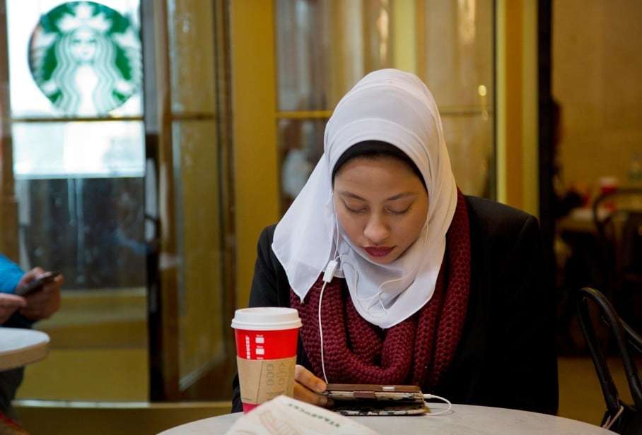 Fifi Youssef pays attention to her iPhone while seated in a Starbucks Coffee, Wednesday, Dec. 16, 2015 in New York. (AP Photo/Mark Lennihan)