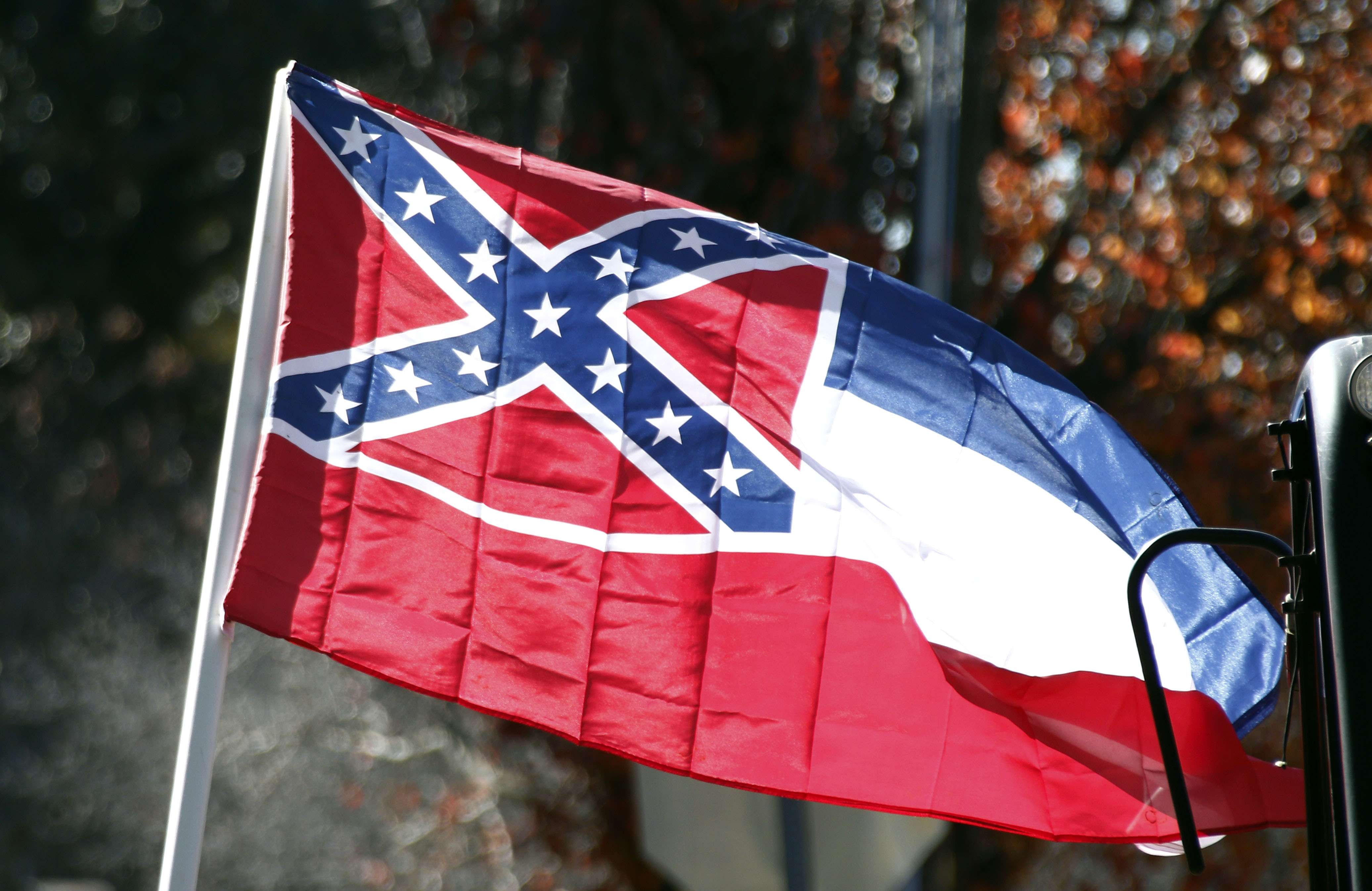 In this Tuesday, Jan. 19, 2016 photo, a state flag of Mississippi is unfurled by Sons of Confederate Veterans and other groups on the grounds of the state Capitol in Jackson, Miss., in support of keeping the Confederate battle emblem on the state flag. Mississippi's attorney general said Wednesday, March 2, that he will defend his state's flag against a lawsuit that seeks to remove its Confederate battle emblem, even though he thinks the flag hurts the state and should change. (AP Photo/Rogelio V. Solis)