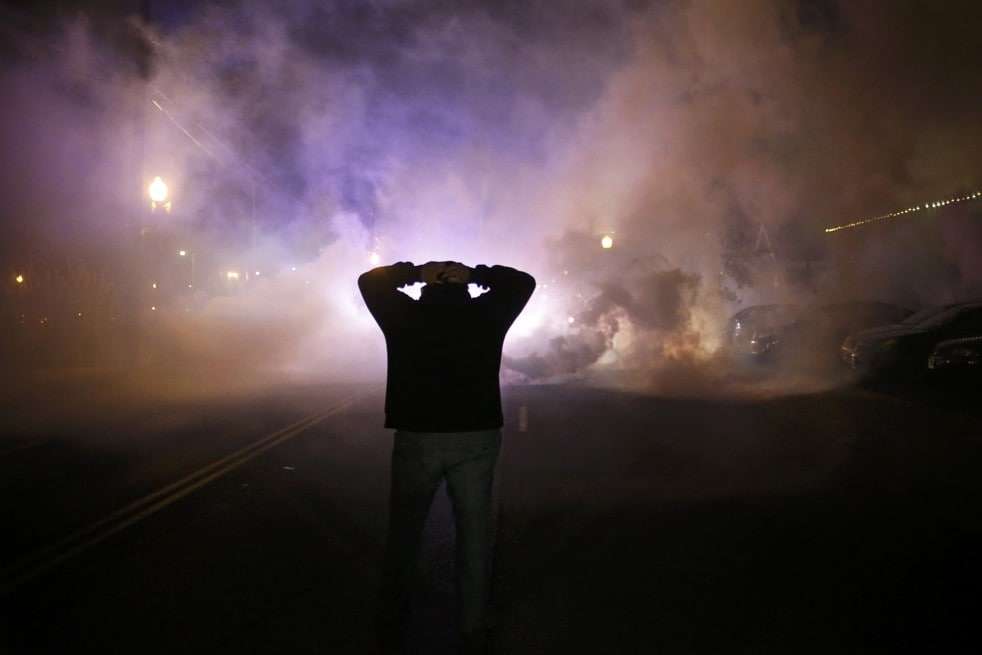 A protester stands with his hands on his head as a cloud of smoke approaches. (Reuters)