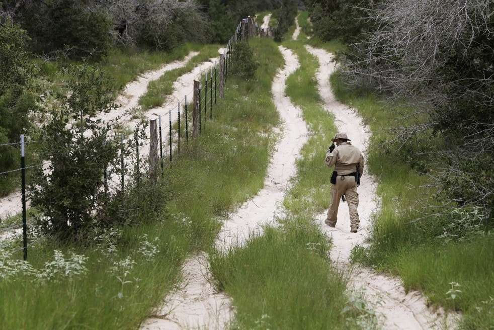 FILE- In this Sept. 5, 2014, file photo, a U.S. Customs and Border Protection Air and Marine agent looks for signs along trail while on patrol near the Texas-Mexico border near McAllen, Texas. A federal judge temporarily blocked President Barack Obama's executive action on immigration Monday, Feb. 16, 2015, giving a coalition of 26 states time to pursue a lawsuit that aims to permanently stop the orders. (AP Photo/Eric Gay, File) 