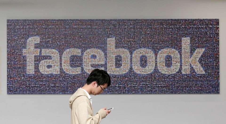 FILE - In this June 11, 2014 photo, a man walks past a Facebook sign in an office on the Facebook campus in Menlo Park, Calif. Facebook's recent effort to force people to adopt its standalone mobile messaging app has privacy-concerned users up in arms. In truth, Facebook Messenger isn't any more invasive than Facebook's main app _or other similar applications. (AP Photo/Jeff Chiu, File)