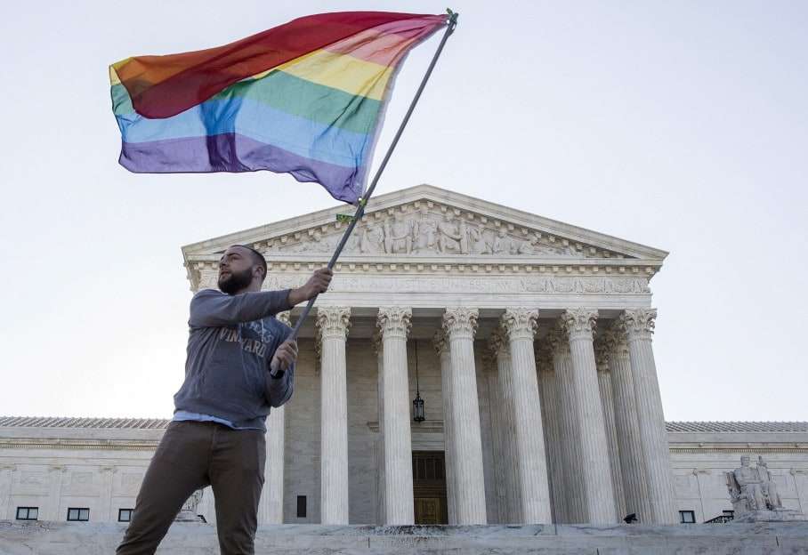 Vin Testa of Washington, DC, waves a gay rights flag in front of the Supreme Court before a hearing about gay marriage in Washington in an April 28, 2015 file photo. The U.S. Supreme Court ruled on June 26, 2015 that the U.S. Constitution provides same-sex couples the right to marry in a historic triumph for the American gay rights movement. The court ruled 5-4 that the Constitution's guarantees of due process and equal protection under the law mean that states cannot ban same-sex marriages. With the ruling, gay marriage will become legal in all 50 states. REUTERS/Joshua Roberts/files