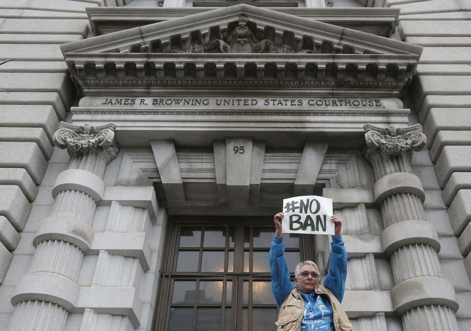 Karen Shore holds up a sign outside of the 9th U.S. Circuit Court of Appeals in San Francisco, Tuesday, Feb. 7, 2017. A panel of appeals court judges reviewing President Donald Trump's travel ban hammered away Tuesday at the federal government's arguments that the states cannot challenge the order. (AP Photo/Jeff Chiu)